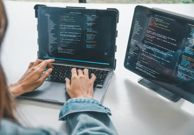 Technician configuring a laptop alongside a second screen