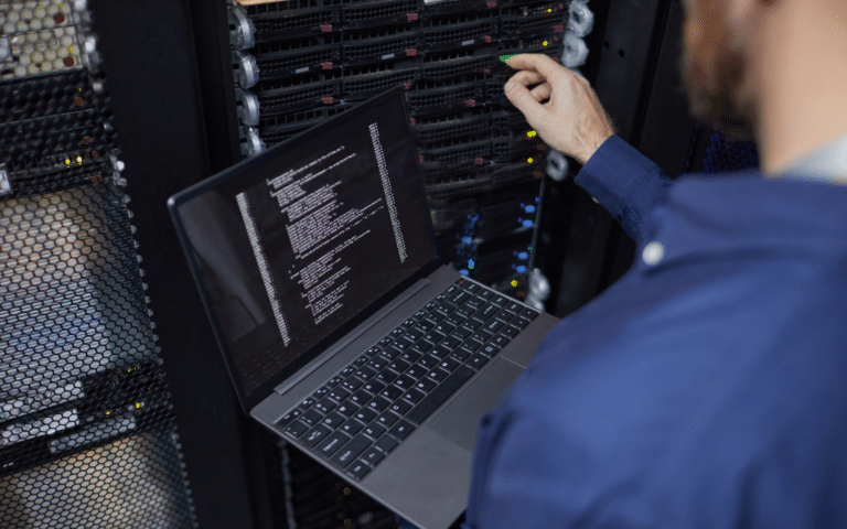 Technician checking equipment against a laptop at an open server cabinet