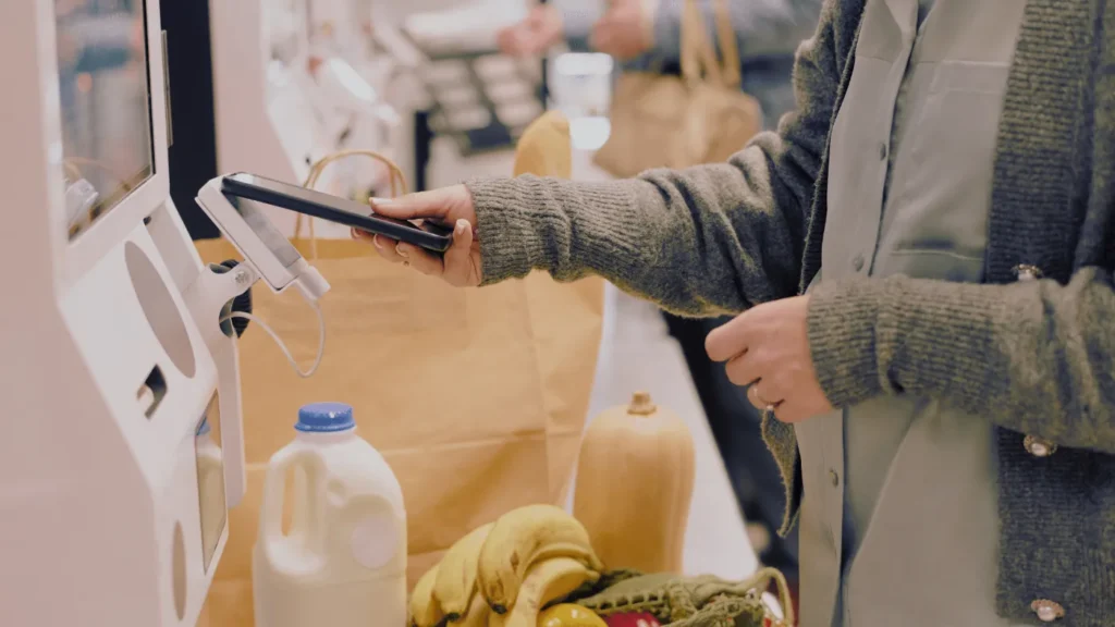 Customer paying by phone at a restaurant self-service POS kiosk