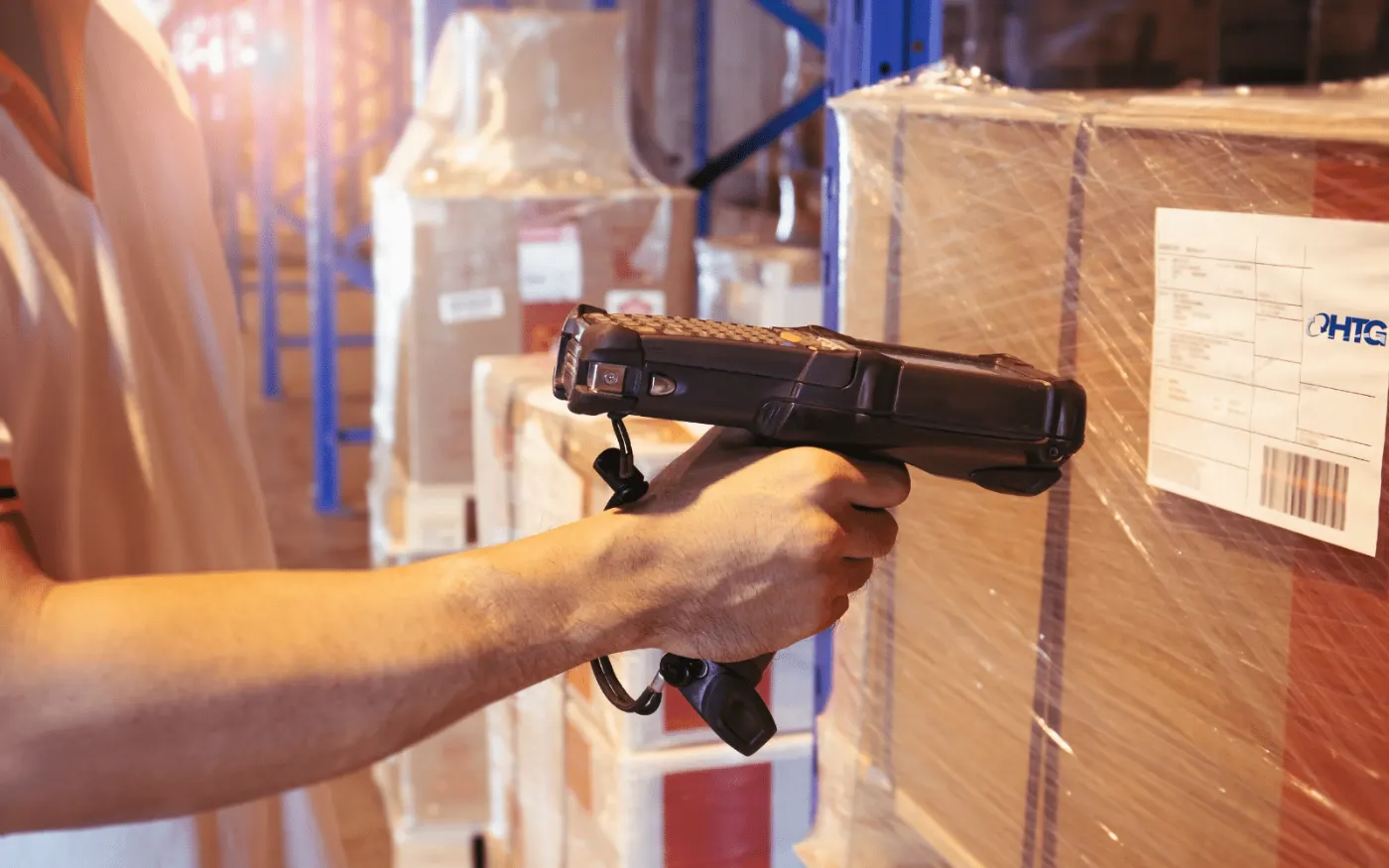 Warehouse worker scanning a barcode label on packaged equipment staged on a pallet