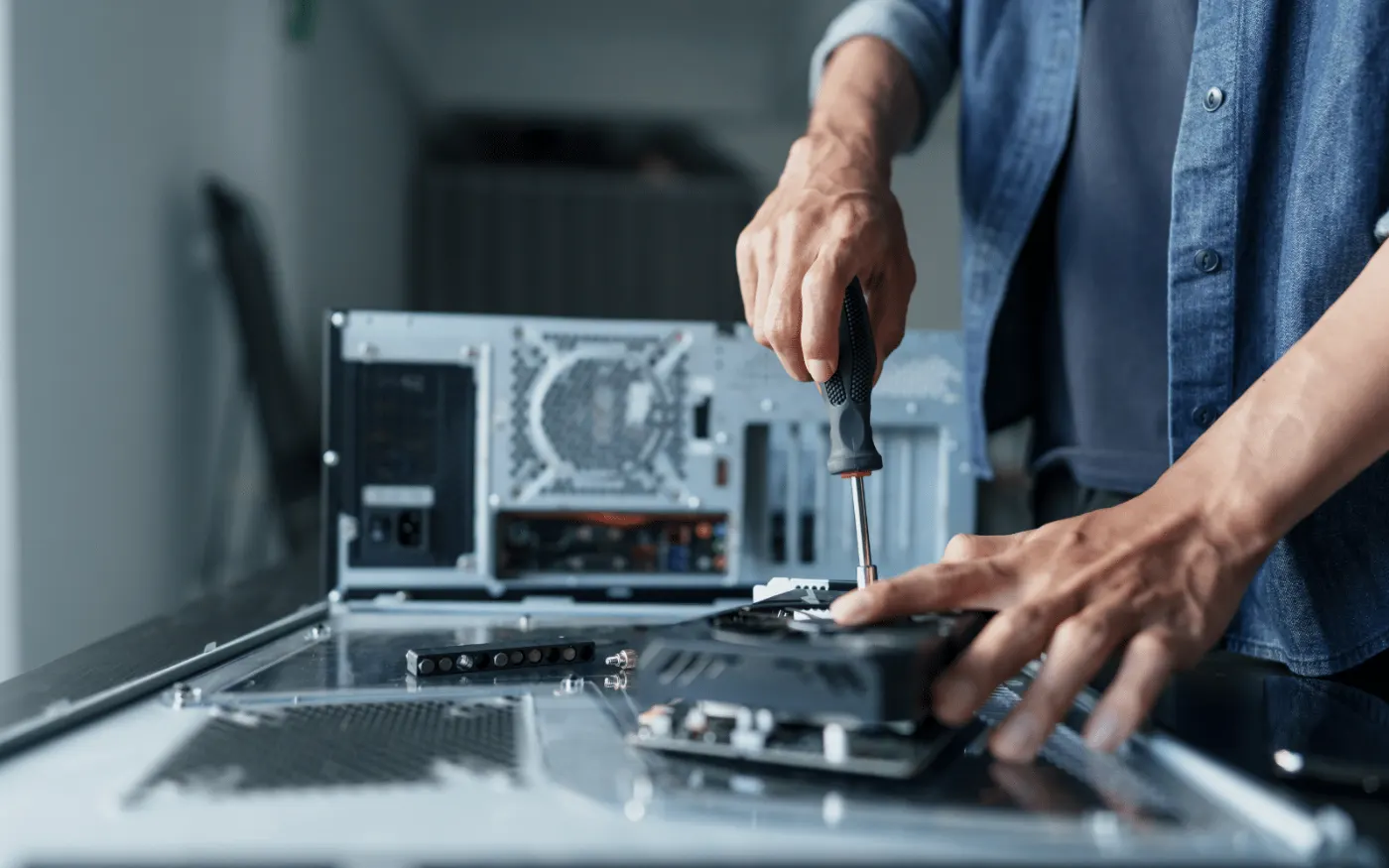 Technician removing a component from an opened server chassis with a screwdriver