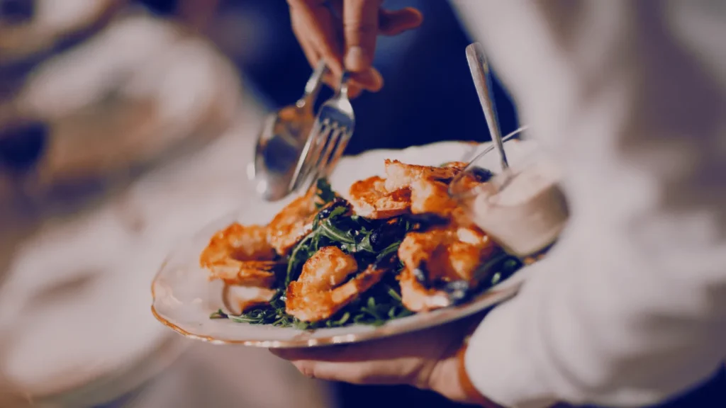 Server carrying a plated dish through a busy dining room
