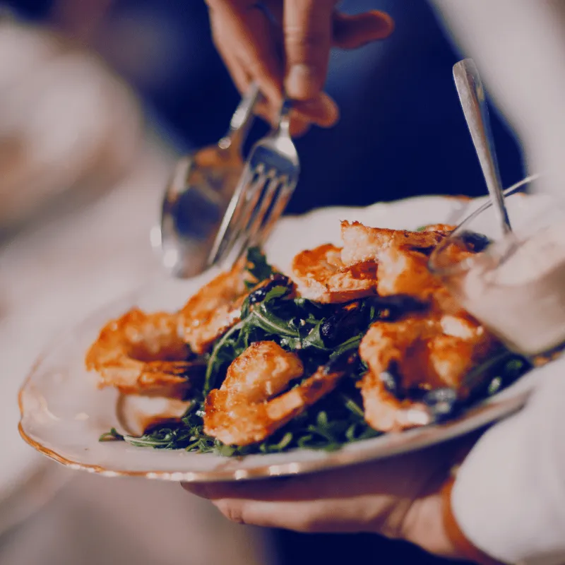 Server carrying a plated dish through a busy dining room