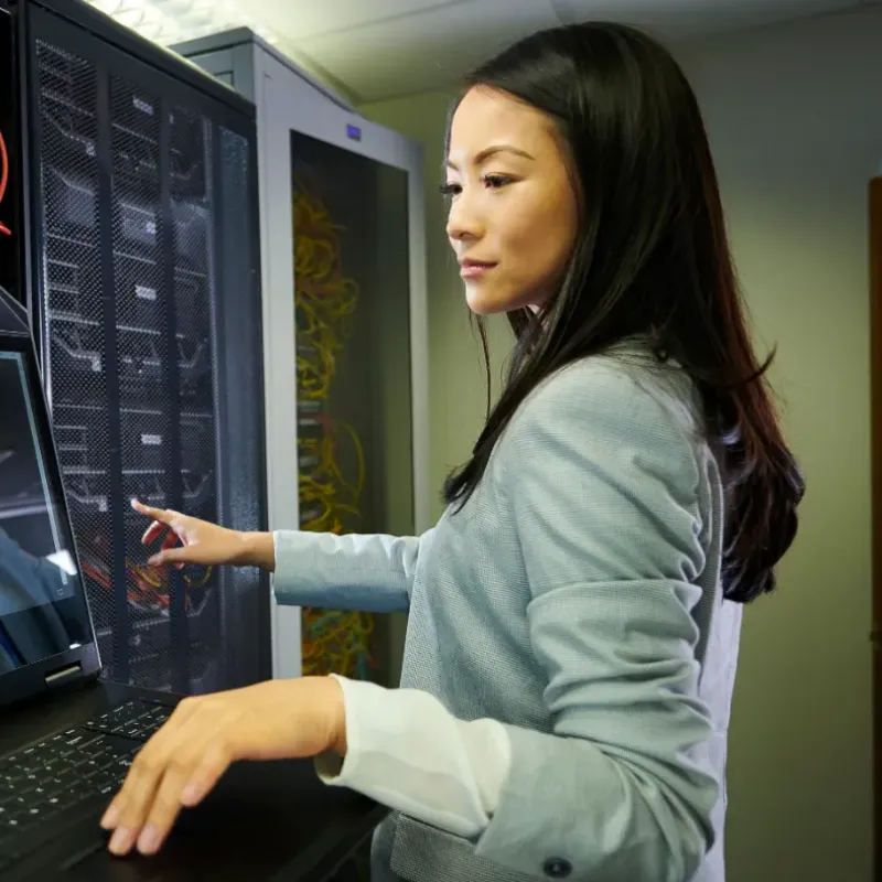 IT technician at a network equipment rack preparing retail technology for a store rollout